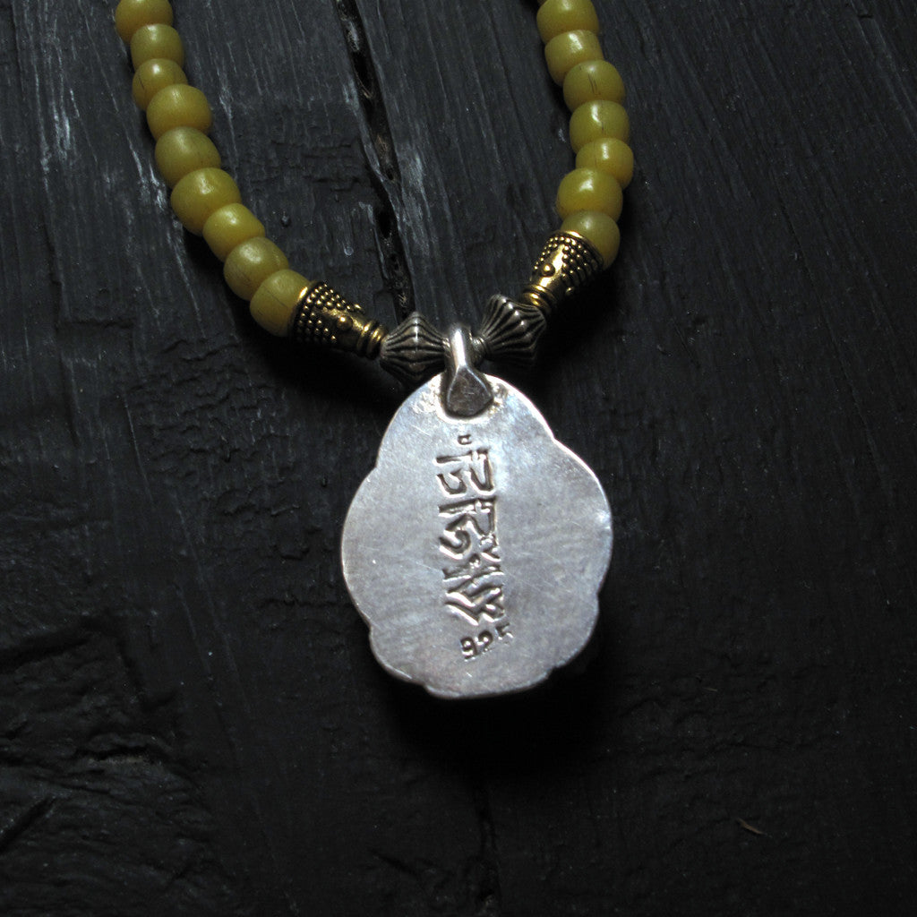 Tibetan seated silver Buddha on glass bead necklace